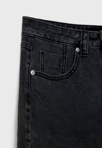 Jeans en denim noir avec une finition texturée, dotés d'une petite poche avant, d'accents métalliques à la taille et de légers détails de couture.