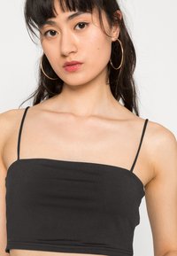 Top preto cropped com alças finas, feito de um tecido suave, apresentando um design ajustado e um decote reto.