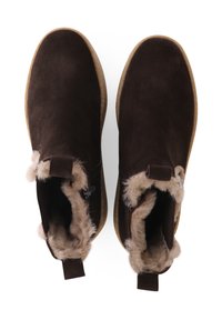 Bruine suède enkelboots met een zachte beige vachtvoering, een platte rubberen zool en trekriempjes aan de achterkant voor gemakkelijke aan- en uittrekken.