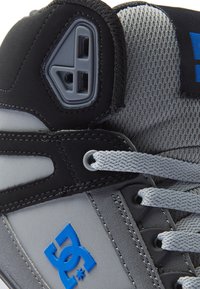 Vysoké tenisky s čierno-šedou farebnou schémou, sieťovinou, syntetickým materiálom a modrým logom DC na boku.