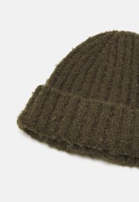 Caciula tricotată cu nervuri de un verde oliv închis, fabricată dintr-un amestec de lână texturat, având un manșon pliat pentru o potrivire strânsă.