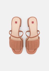 Kamelin väriset korkokengät, joissa on poimutettu etuhihna, ohuet nilkkahihnat ja neliömäinen yksityiskohta sisäpohjassa.