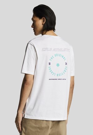 Hvid bomulds t-shirt med rund hals, korte ærmer, med trykt grafik på ryggen med cirkulært design og tekst i teal og lilla.