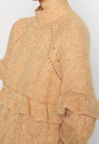 Chunky Strickpullover, hellorange, hoher Kragen, strukturiert mit Rippenmuster, mit Rüschenakzent am Saum und zarten Durchbruchmustern.