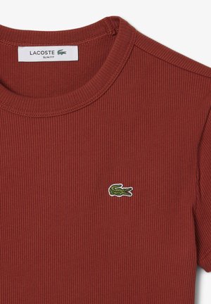 Red ribbed T-shirt with a crew neck, featuring a green and white embroidered crocodile logo on the left chest. Slim fit design.