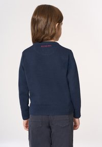 Maglione in maglia blu navy con scollo arrotondato e polsini a coste; presenta in ricamo rosa il testo "U.S. Polo Assn." sulla schiena.