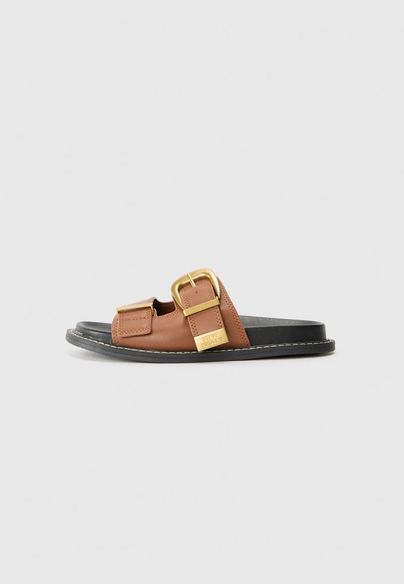 Sandale à glissière en cuir brun avec deux accents de boucle, une semelle noire et un détail cousu le long du bord. Design plat et ouvert au niveau des orteils.