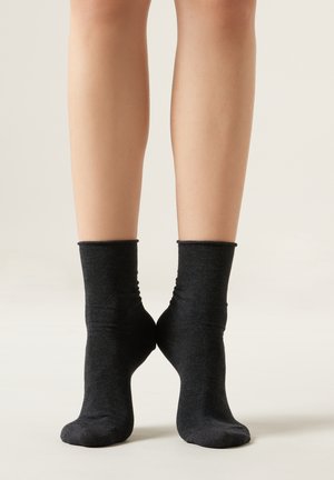 Schwarze Knöchelsocken aus weichem, dehnbarem Material mit glatter Oberfläche und einem schlichten, umgeschlagenen Design.