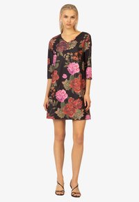Blumenmusterkleid aus schwarzem Stoff mit V-Ausschnitt und dreiviertel Ärmeln. Es hat große rosa und rote Blumen mit grünen Blättern und floralen Akzenten.