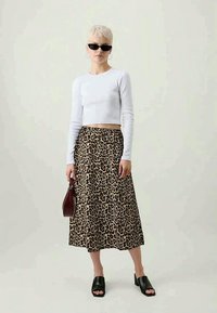 Balta garo piedurkņu cropped krekls, brūns leopardu raksta midi svārki, melni masīvie papēža zābaki un bordo rokassoma. Saulesbrilles un minimālas rotaslietas.