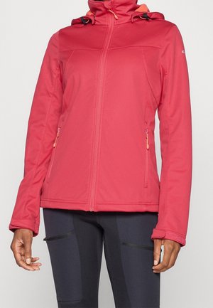 Osoba ubrana w dopasowaną czerwoną kurtkę na zamek z kapturem i kieszeniami na zamek po bokach, w komplecie z czarnymi spodniami z detalami na zamki.