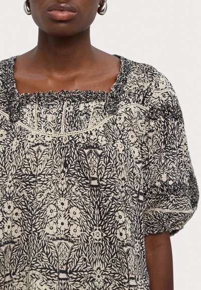 Sorte og kremmønstret bluse med firkantet hals, puffede ermer og intrikate blonder detaljering langs kantene. Laget av lett stoff.
