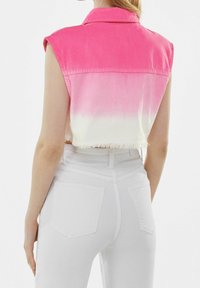 Gilet di jeans cropped con un effetto ombré da rosa a bianco, con colletto e orlo sfrangiato. Abbinato a pantaloni bianchi a vita alta.