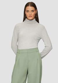 Hellgrauer Rollkragenpullover mit langen Ärmeln und weicher Textur. Kombiniert mit hoch taillierten, gefalteten grünen Hosen. Schlichtes und elegantes Design.