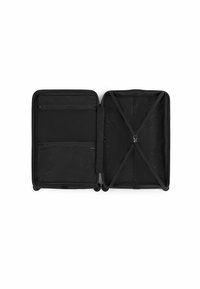 Black travel suitcase with a smooth exterior, interior mesh pockets, cross straps for securing contents, and four wheels for mobility.