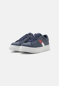 Sneaker blu navy con suola in gomma bianca, dotate di tomaia in pelle liscia, design con lacci e accenti diagonali rossi e bianchi.