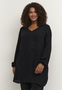 Schwarze Tunika mit langen Ärmeln und V-Ausschnitt, mit lockerer Passform, strukturiertem Stoff und seitlichen Schlitzen am Saum. Einfaches und vielseitiges Design.