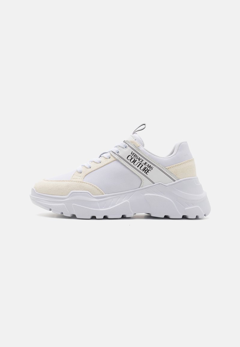 Sneaker bianca con una combinazione di tessuto morbido e dettagli in suede, una suola chunky e un logo ben visibile sul lato.