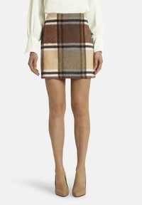 Vilnas maisījuma mini svārki ar brūnu, bēšu un krēmkrāsas rūtaino rakstu, akcenti melnā krāsā. Audums ir mīksts ar strukturētu apdari.