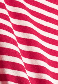 Czerwono-białe poziome paski dzianiny z delikatnymi fałdami i widocznymi detalami tekstury.