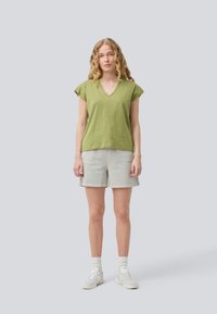 Oliven grønn bomull V-hals topp med korte ermer, sammen med lysegrå linshorts og hvite joggesko. Enkel og uformell design.