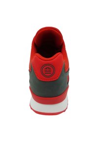 Sneaker rosso e grigio con tomaia in tessuto texturizzato, colletto imbottito e suola intermedia bianca con un logo sul tallone.