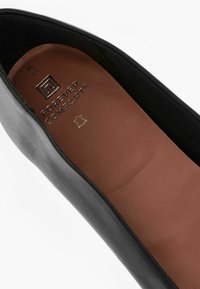 Chaussure noire à enfiler avec un cuir lisse à l'extérieur et une semelle intérieure en cuir marron rembourrée. Présente l'empreinte de la marque "Forever Comfort" embossée sur la semelle intérieure.