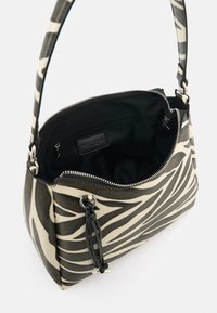 Zebra-striped handbag with a textured surface in black and cream. Features a zip closure and an interior pocket. Adjustable strap.