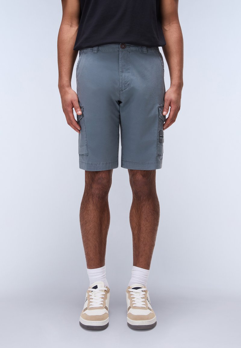 Gray cargo shorts with two side pockets, a button closure, and a straight cut. Worn with beige and white sneakers and white crew socks.