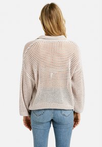Leichter Pullover mit Rundhalsausschnitt aus einem Netzstrickmuster, beige Farbe, lange Ärmel, mit lockerer Passform und gerippten Bündchen.