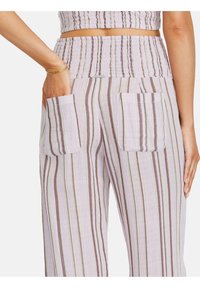 Spodnie z wysokim stanem i szerokimi nogawkami w pionowe paski w pastelowych kolorach, z dwoma naszywanymi kieszeniami z tyłu, noszone z dopasowanym krótkim topem.