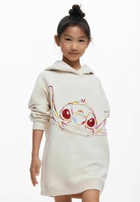 Tejfehér kapucnis pólóruha, hímzett karakterdizájnnal piros, sárga és kék színekben. Puha anyagú, laza fazon, hosszú ujjak.