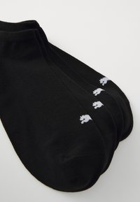 Svarta ankelsockor i tyg med en jämn textur. Har en vit logotypdesign på kanten. Sattes av tre par.