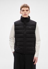 Μαύρο γιλέκο με επένδυση, ψηλό γιακά, κλείσιμο με φερμουάρ και δύο πλαϊνές τσέπες. Διαθέτει διακριτικό λογότυπο στο στήθος και απαλό, υφασμάτινο φινίρισμα.