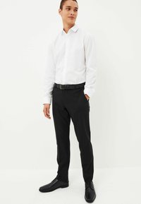 Weißes Button-Up-Hemd, schwarzer Gürtel, schwarze Hose und schwarze Schuhe. Glatter Baumwollstoff, taillierte Passform und klassisches Kragen-Design.