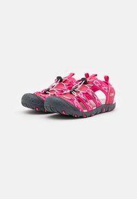 Pink outdoor sandals with elastic straps, rubber soles, and a textured finish. Features a secure lacing system and reinforced toe area.