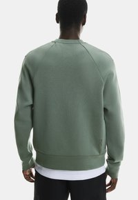 Zielony bawełniany sweter z teksturowanym wykończeniem, rękawami raglanowymi, ściągaczami u dołu i na rękawach oraz akcentem z logo na plecach.