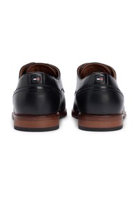 Μαύρα δερμάτινα παπούτσια με λείο φινίρισμα, καφέ ξύλινη φτέρνα και ρ αφές διακοσμητικές. Διαθέτουν μικρό λογότυπο κοντά στη φτέρνα.