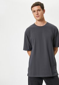 Grå bomulds T-shirt med rund halsudskæring, korte ærmer og en afslappet pasform. Blød tekstur og minimalistisk design.