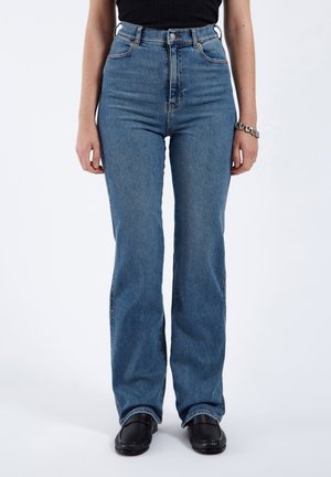 High-waisted blue denim jeans with a flared leg design, featuring front pockets and metal button closure. Smooth texture, classic five-pocket style.