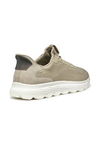 Sneaker beige con tomaia in tessuto strutturato e finiture in camoscio. Presenta una suola bianca ondulata e un inserto sul tallone per facilitare l'indossamento.