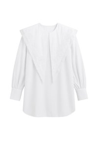 Blusa bianca a maniche lunghe con ampio colletto a punta caratterizzato da ricami floreali e bordi ondulati, polsini abbottonati e una piega centrale anteriore.
