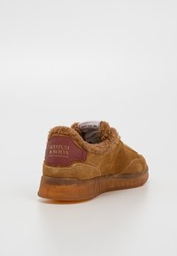 Baskets en daim marron avec doublure en laine, semelle translucide et logo "Scotch & Soda Amsterdam" sur la languette talonnière.