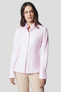Jasnoróżowa koszula z długim rękawem, z ostrym kołnierzykiem, posiadająca guziki z przodu, dopasowany krój oraz gładki materiał bawełniany.