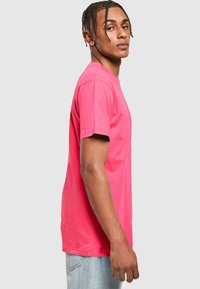 T-shirt in cotone rosa con maniche corte, scollo rotondo e vestibilità rilassata, abbinato a jeans in denim azzurro chiaro.