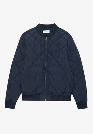 Chaqueta bomber acolchada en navy con cremallera frontal, puños acanalados, bolsillos laterales y un parche circular con logo en el pecho. Fabricada con material ligero.