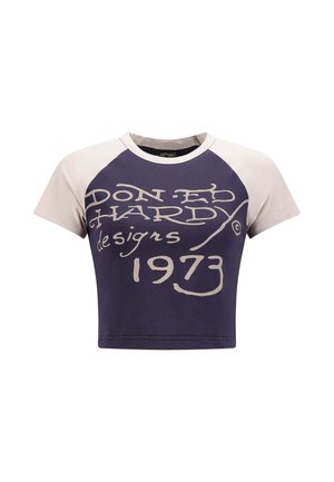 Korte mouwen cropped t-shirt met een marineblauwe body en crèmekleurige raglanmouwen, grote crèmekleurige tekst met de opdruk "DON ED HARDY designs 1973."