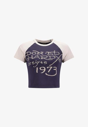 Korte mouwen cropped t-shirt met een marineblauwe body en crèmekleurige raglanmouwen, grote crèmekleurige tekst met de opdruk "DON ED HARDY designs 1973."