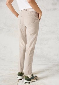 Ljust beige byxor med rak passform, med två bakfickor. Bärs med gröna och tanfärgade sneakers. Slät tyg med subtil textur.