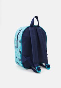 Sac à dos avec une base marine, des côtés bleu clair arborant des motifs de dessins animés, des bretelles réglables et une poignée supérieure pour le transport.